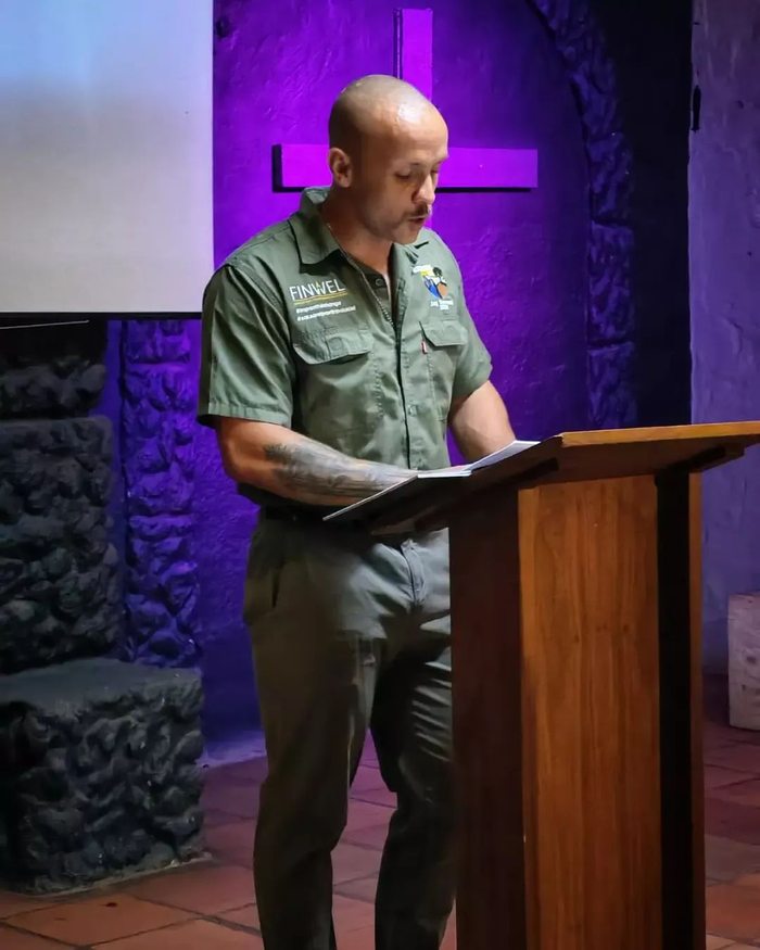 Stefan reading at the pulpit, purple stage light behind him